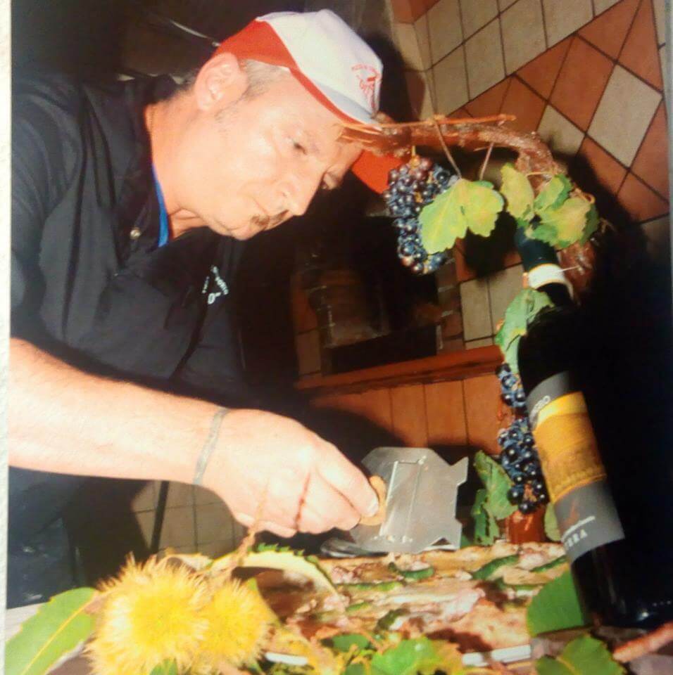 Foto del pizzaiolo al lavoro mentre stende l'impasto su marmo infarinato